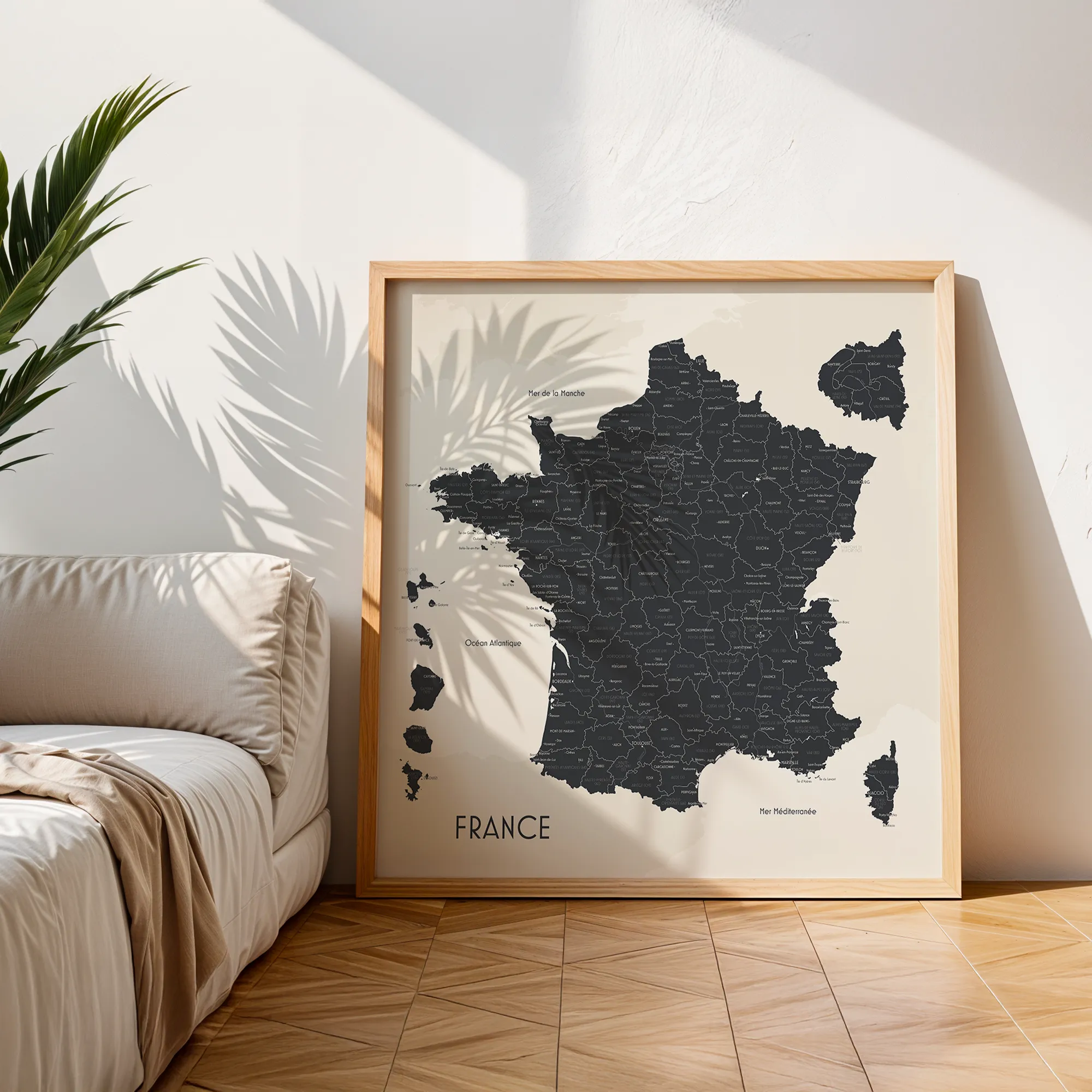 Carte de France des départements encadrée posée contre un mur